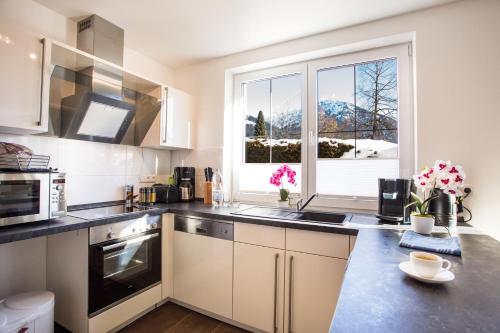 a kitchen with white cabinets and a large window at Haus Alpgaustraße - Ferienhäuser Alpenglück in Oberstdorf