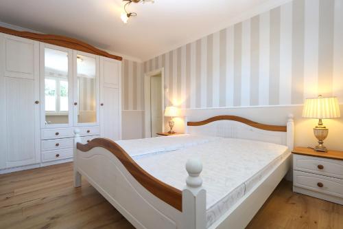 a bedroom with a white bed with striped walls at Haus Ostseenordstern Nienhagen in Nienhagen