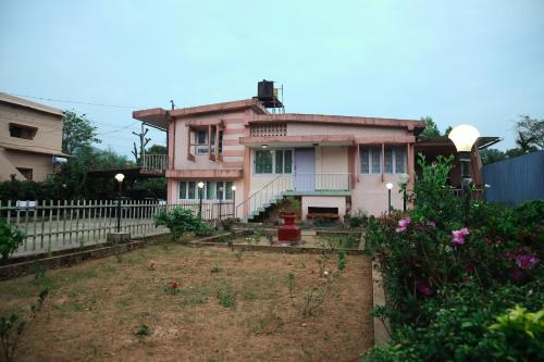 a pink house with a garden in front of it at DASWAL GARDEN HOME in Madikeri