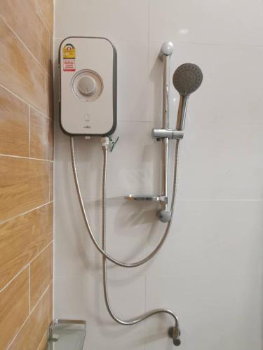 a shower in a bathroom with a hose attached to the wall at NST Boutique เอ็นเอสทีบูทีค in Ban Pak Phun