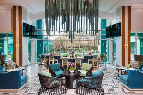 a lobby with chairs and tables and a chandelier at Hotel Landy Orlando Universal Blvd, a Tribute Portfolio Hotel in Orlando