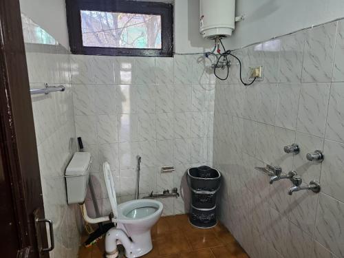 a small bathroom with a toilet and a window at Beholden Stay and Cafe in Manāli