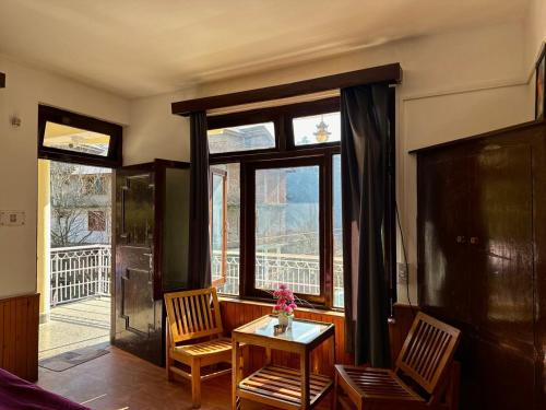 Habitación con 2 sillas, mesa y ventana en Beholden Stay and Cafe, en Manali