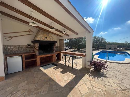 an outdoor kitchen with a fireplace and a swimming pool at Villa Sergi in Les tres Cales