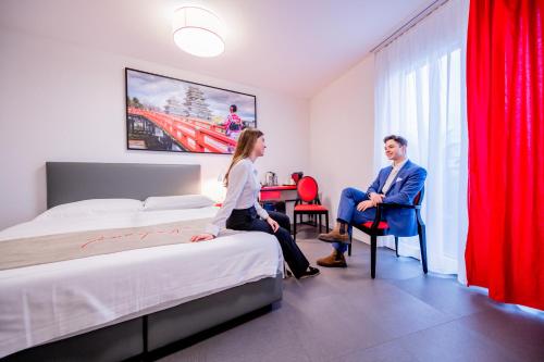 een man en vrouw die op bedden in een hotelkamer zitten bij "The Freddie Mercury" Hotel in Montreux