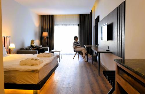 a hotel room with a bed and two women sitting in chairs at Pamukkale Kaya Thermal Spa Hotel in Pamukkale