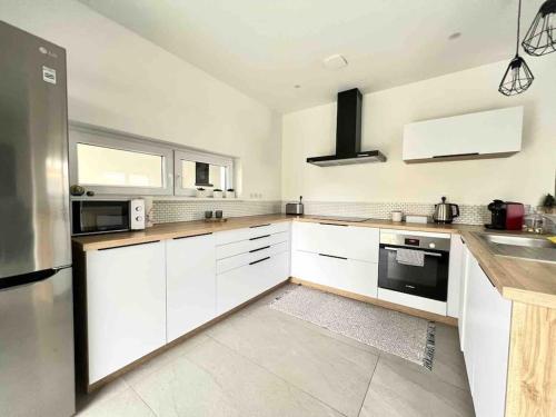 une grande cuisine avec des placards blancs et un évier dans l'établissement Bel appartement en plain-pied 5 min de Colmar, à Wickerschwihr