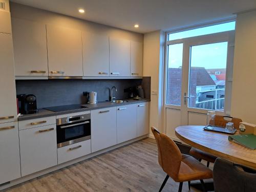 een keuken met witte kasten en een tafel en een raam bij 107,5 Nieuw appartement met sauna in Westkapelle