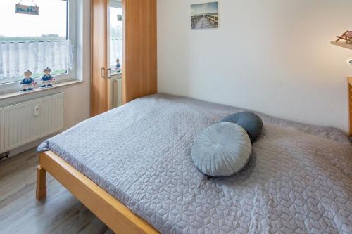 ein Schlafzimmer mit einem Bett mit einem blauen Kissen darauf in der Unterkunft Friesenstübchen in Dornumersiel