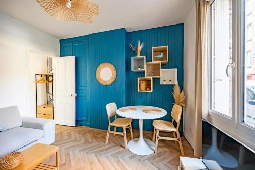 un salon avec une table et un mur bleu dans l'établissement La brise marine, au Havre