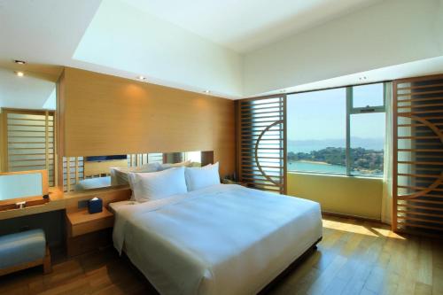 a bedroom with a large white bed and a desk at Swiss Grand Xiamen-Harbour View in Xiamen