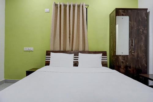 a bedroom with a large white bed and a window at Hotel Mango Tree Lodging in Pune