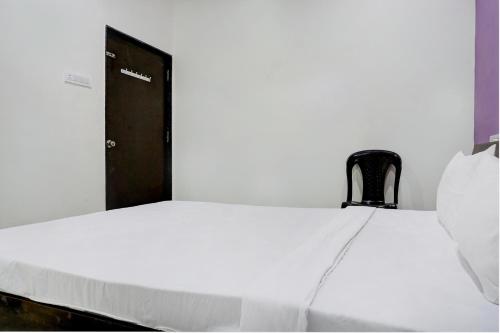 a white bed with a chair next to a door at Hotel Mango Tree Lodging in Pune