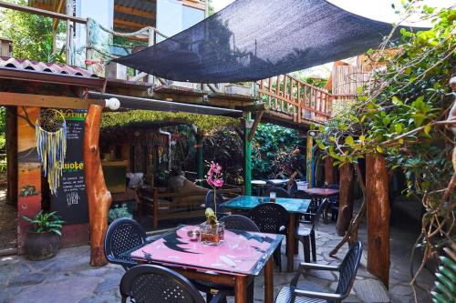 an outdoor patio with tables and chairs and a building at Mantis and Moon Surf Paradise & Adventure Lodge in Hibberdene
