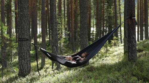 a woman laying in a hammock in a forest at Cozy Stuga - Mountain View in Ramsele