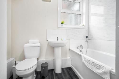 uma casa de banho branca com um WC e um lavatório em 2 Bedroom Apartment - West Brom - Netflix - Wifi - Parking - Excellent Value - WBA em West Bromwich