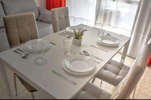 - une table à manger blanche avec des assiettes blanches et de l'argenterie dans l'établissement Ritual Sevilla, piedra preciosa, à Séville