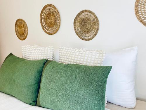 a bed with green pillows and baskets on the wall at Appart Brussels EXPO & ATOMIUM in Grimbergen