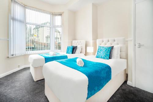 Duas camas num quarto branco com toques azuis em 2 Bedroom Apartment - West Brom - Netflix - Wifi - Parking - Excellent Value - WBA em West Bromwich