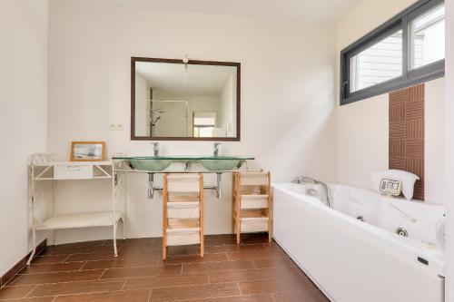 Saint-ArmelにあるMaison avec piscine pour dix personnesの洗面台、浴槽、鏡のあるバスルーム