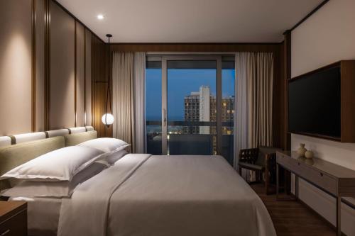 a bedroom with a large bed and a large window at Sheraton Grand Tel Aviv in Tel Aviv