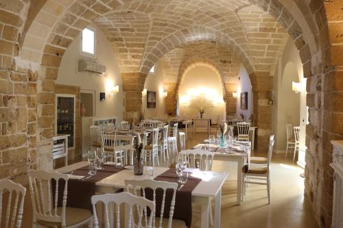 restauracja z białymi stołami i krzesłami w budynku w obiekcie Tenuta Monacelli Lecce w mieście Lecce