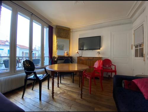 a living room with a table and chairs and a tv at Jolie appartement 4 pièces in Montreuil