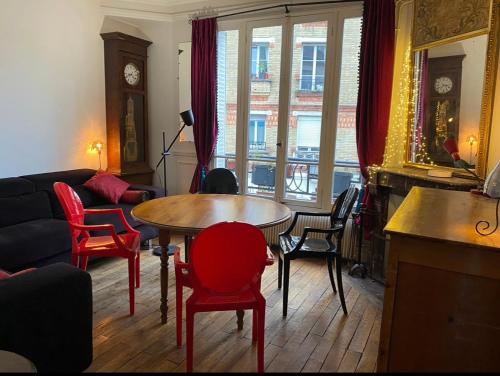 a living room with a table and red chairs at Jolie appartement 4 pièces in Montreuil