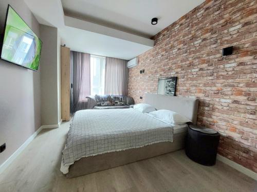 Un dormitorio con una pared de ladrillo y una cama en Ботаника,новострой,уютная однушка, en Chişinău