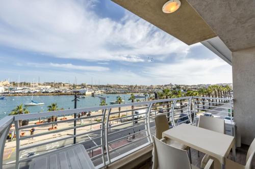 einen Balkon mit Tischen und Stühlen und Blick auf das Wasser in der Unterkunft Large & Modern 2BR Seafront Apartment with Large Balcony - Close to Saint Julian's, Sliema, & Manoel Island in Gżira