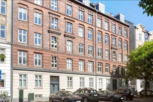 a large brick building with cars parked in front of it at Frederiksberg in Copenhagen