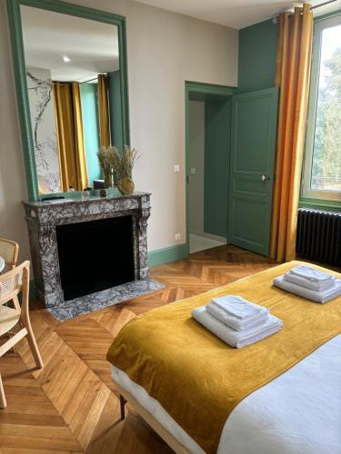 - une chambre avec une cheminée et un lit avec 2 serviettes dans l'établissement La Parenthèse Fléchoise, Chambre Armand, à La Flèche