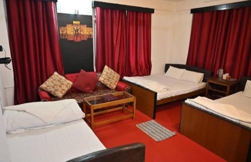 een kamer met 2 bedden, een bank en rode gordijnen bij Hotel Birdie's Nest in Darjeeling