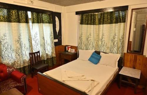 een slaapkamer met een bed, een stoel en ramen bij Hotel Birdie's Nest in Darjeeling