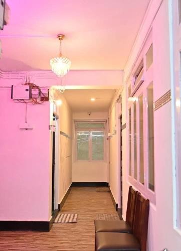 a hallway with pink walls and a chandelier at Hotel Birdie's Nest in Darjeeling