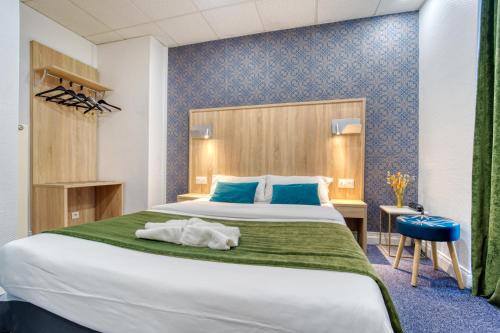 een slaapkamer met een groot bed en een blauwe muur bij Hôtel Escurial - Centre Gare in Metz