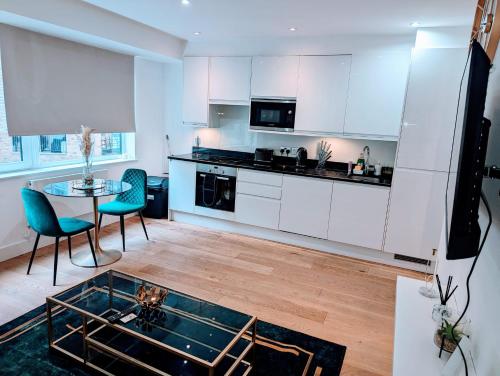 a kitchen with white cabinets and a glass table at x2 suites x2 bedroom with free parking & wifi in Croydon