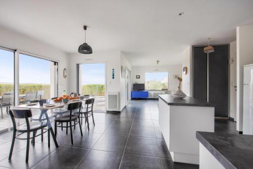 une cuisine et une salle à manger avec une table et des chaises dans l'établissement Vue mer - Maison neuve avec jardin, à Erquy
