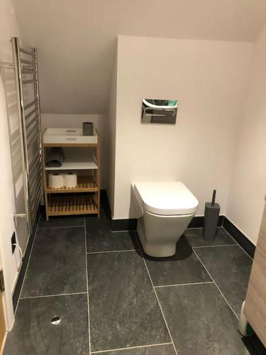 a bathroom with a white toilet and a tile floor at Larks Rise in Bruisyard