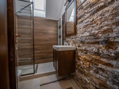 ein Badezimmer mit einem Waschbecken und einer Ziegelwand in der Unterkunft Harghita Traditional House in Szèkelydobò