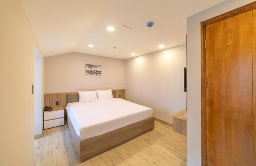 a bedroom with a white bed and a bathroom at Nature Hotel - Win Happy in Da Lat