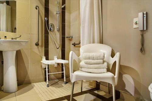 La salle de bains est pourvue d'une chaise blanche et d'une douche. dans l'établissement The RidgePoint Hotel, à Witbank