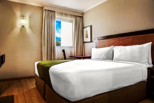 um quarto de hotel com uma cama grande e uma janela em The RidgePoint Hotel em Witbank