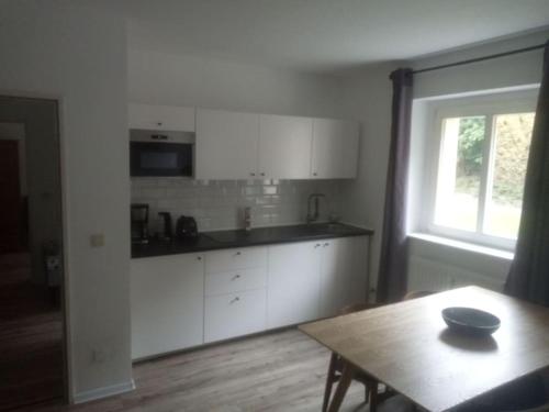 a kitchen with white cabinets and a table and a window at ELBENLAND SÄCHSISCHE SCHWEIZ II - Komfortable 2-Raum-Wohnung im Herzen der sächsischen Schweiz in Sebnitz