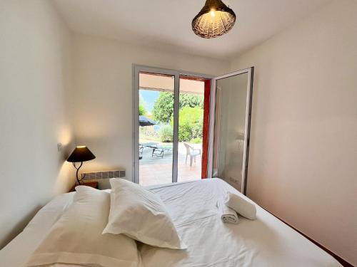 - une chambre avec un lit blanc et une porte coulissante en verre dans l'établissement Appartement une chambre dans residence calme, à Propriano