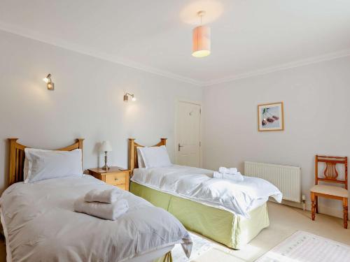 1 dormitorio con 2 camas con sábanas blancas y silla en 3 Bed in Conon Bridge CA388 en Cononbridge