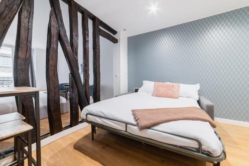 une chambre avec un lit avec un mur bleu dans l'établissement Imhost 7 -Cosy apart Batignolles/Galerie Lafayette, à Paris