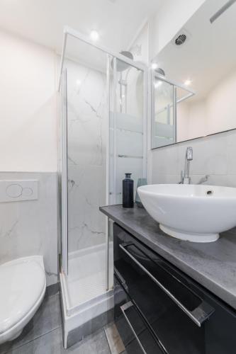 une salle de bain blanche avec un lavabo et des toilettes dans l'établissement Imhost 7 -Cosy apart Batignolles/Galerie Lafayette, à Paris