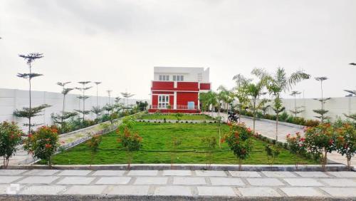 un edificio rojo con un jardín delante de él en Rama Farms, en Sangamner