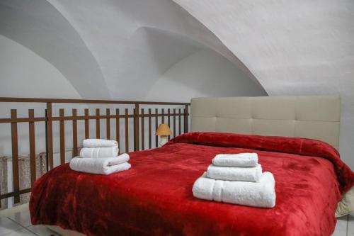 - une chambre avec un lit rouge et des serviettes dans l'établissement TARANTA HOUSE - Notte della Taranta casa con giardino, à Melpignano